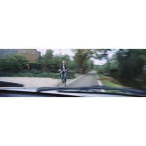  Woman Riding a Bicycle Viewed Through a Windshield of a Car 